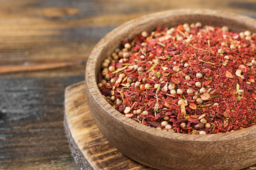 Seasoning for meat in a wooden bowl on a brown wooden table. Close-up with space for text