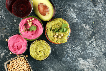 A variety of colored hummus, beetroot hummus, hummus with avocado on background. Veggie Clean eating, dieting, vegetarian party food.