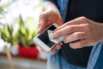 Man using a disinfection wipe on a phone
