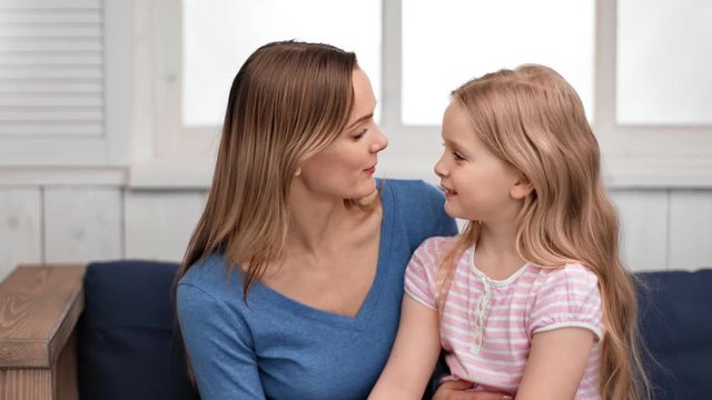 Mother talking with cute daughter playing touching nose. Medium close up shot on 4k RED camera
