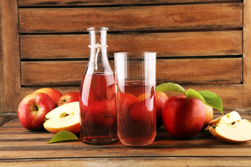 Apple cider drink and organic apples with leaves on table