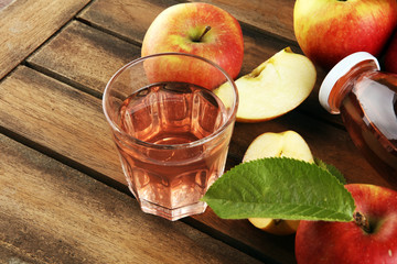 Apple cider drink and organic apples with leaves on table