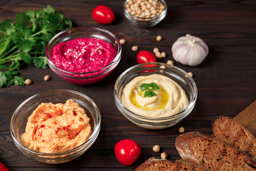Variety of Middle eastern hummus with chickrea, beetroot, carrot on wooden table