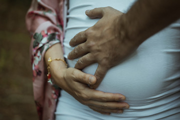 Mujer embarazada junto a su marido. Se tocan la barriga.