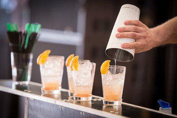 Barman pouring drinks into glasses