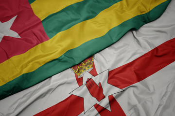 waving colorful flag of northern ireland and national flag of togo.