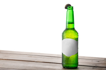 Bottle of beer with an open cap on a table with isolated background