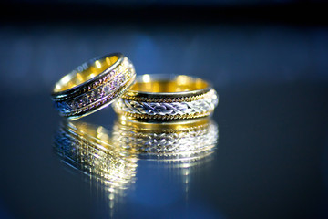 Wedding rings for weddings lie on a mirror reflecting surface.