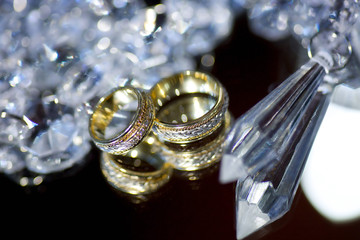 Wedding rings for weddings lie on a mirror reflecting surface.