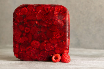 Red frozen raspberry cube near fresh raspberry. Creative photo. Copy space.