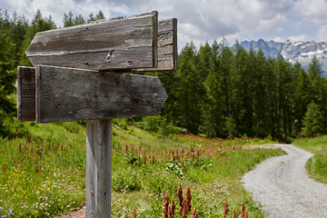 Wooden sign on a sandy road.