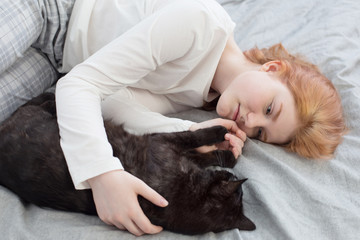 beautiful teenager girl with black cat on bed at home