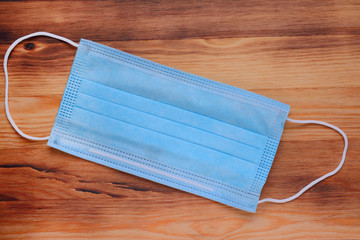 Medical protective mask on a wooden surface, top view