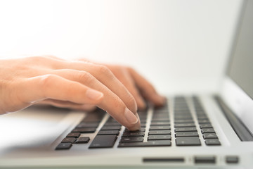 Hands writing on a Keyboard of a Laptop or Notebook in Home Office