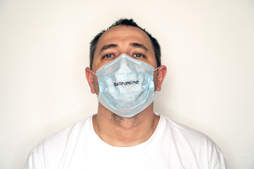 Portrait of an overgrown and unshaven man in a medical mask and the inscription Quarantine on the...