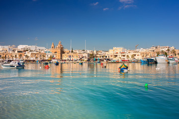 Fototapeta na wymiar Blue lagoon at the Mediterranean Village of Marsaxlokk, Malta