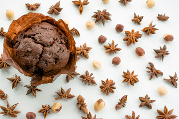 chocolate muffin on a background of brown nuts and star anise. sweet baking seasoning. the view...