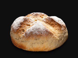 Wheat bread. Round peasant bread isolated on a black background.