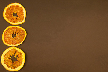 Dehydrated slices of grapefruit on a brown background.