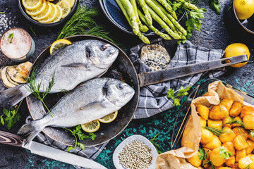 Frischer roher Dorado oder Seebrasse mit Spargel, Gewürzen, Kräutern, Zitrone und Salz auf...