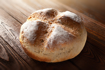 Homebaked bread. Wheat hot bread on a wooden background.