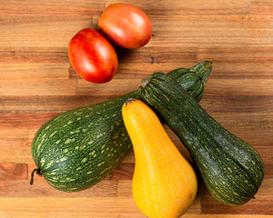 zuchinis verdes y amarillo, tomates rojos sobre tabla de madera de pino