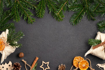 Zero waste christmas concept. Packed in natural fabric gifts and decorations from natural materials on black table, top view, copy space