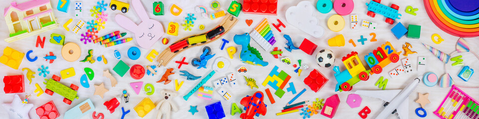 Variety of plastic and wooden kids toys on light wooden background