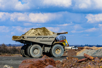 Huge dump truck loaded with iron ore on a gravel road