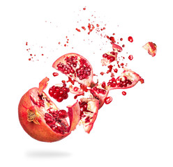 Chopped pomegranate in the air with drops of juice close up on a white background