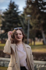 Portrait of a stylish woman in sunglasses in windy weather with closed eyes.