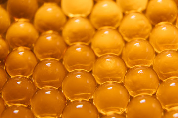 Fish oil capsules. Many round tablets of red-orange color.