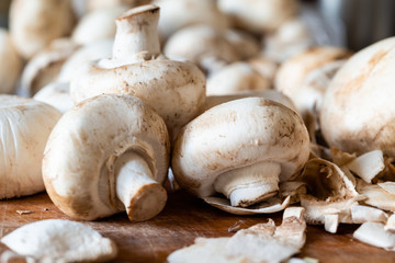 Peeling of fresh champignon mushrooms on a wooden cutting board. Side view. Close-up. Autumn background.
