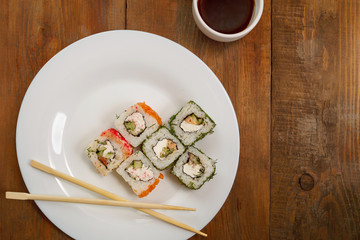 Assorted rolls with salmon and masago caviar on a white plate soy sauce.