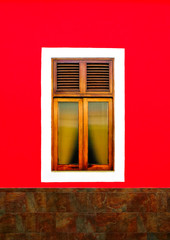 Simple classic wooden window in a bright red wall.