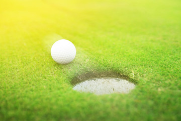 Golf ball near hole in park on sunny day. Space for design