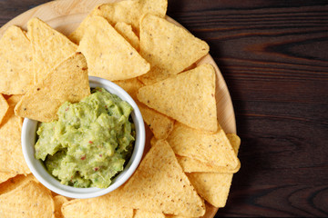 Guacamole avocado sauce with nachos on a wooden background