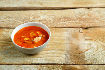 Dish with thai tom yam soup on a wooden table.