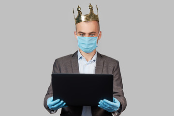 Young businessman in a crown and a protective face mask and gloves. Stay home during quarantine of coronavirus Covid-19. Empty space for text.