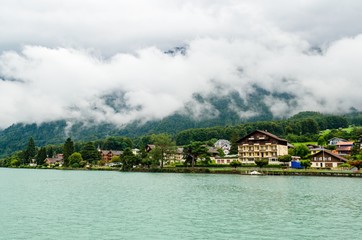 Brienzersee, lake of Brienz with cloudy alps mountains in clouds. Houses of Interlaken, Canton Bern, Switzerland