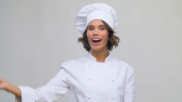 cooking, culinary and people concept - portrait of happy smiling female chef in toque making delicious gesture over grey background