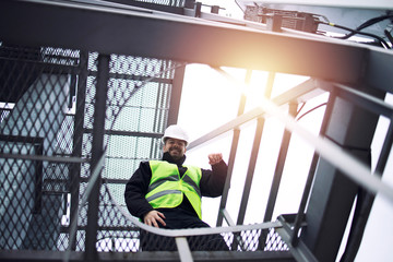Industrial factory worker in protective equipment standing on metal staircase of production plant. Industry and energy. © littlewolf1989