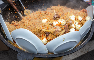 Cooking traditional oriental pilaf in a large cauldron