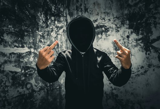 Man In Hooded Jacket Showing Middle Finger While Standing Against Old Wall