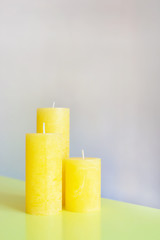three large yellow candles on a gray background
