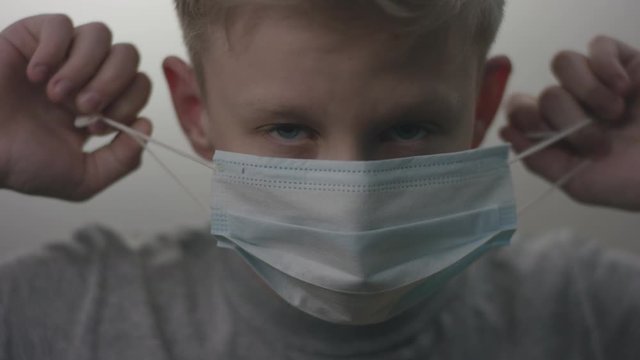 Closeup Shooting Of A Young Caucasian Kid Taking Off A Virus Mask After Cancelation Of A Quarantine Due To Covid19 Epidemic