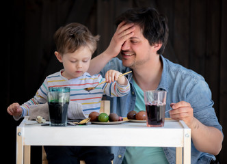 Father and son painting easter Eggs on a table