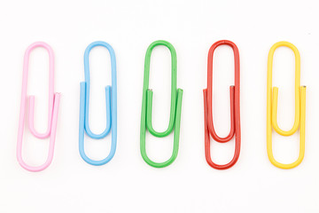 Multi colored paper clips on white.