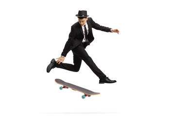 Fototapeta na wymiar Young man in an elegant suit jumping with a skateboard