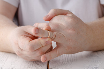 Man signing divorce decree and taking off wedding ring, copy space, blurred background